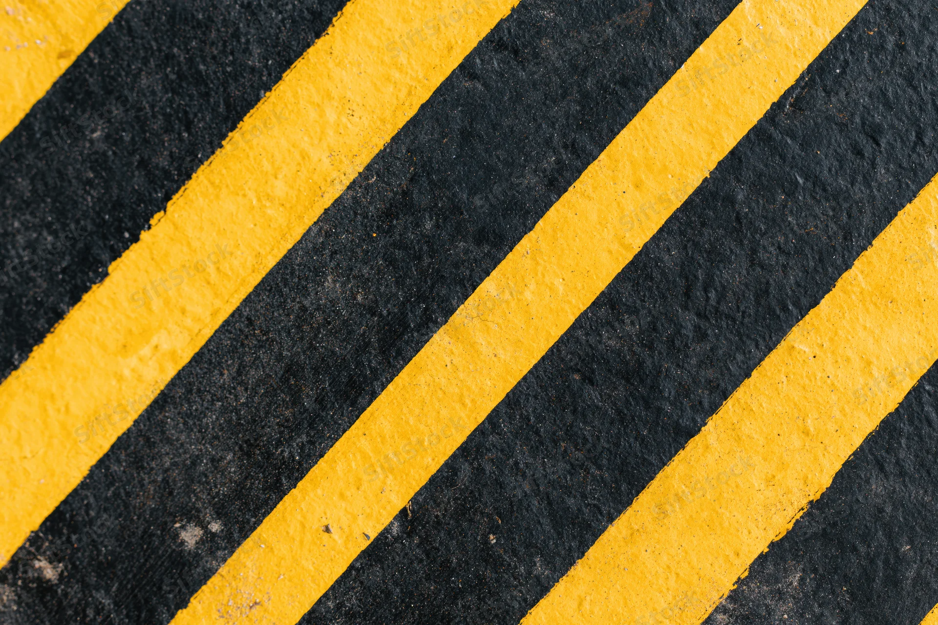 Diagonal yellow and black stripes painted on an industrial floor surface