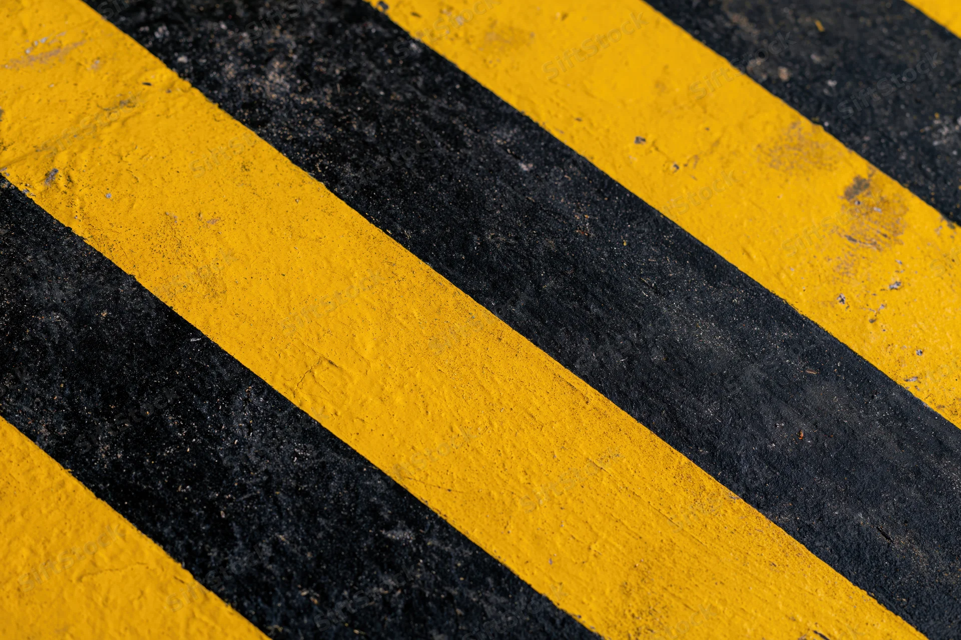 Diagonal yellow and black stripes painted on an industrial pavement surface
