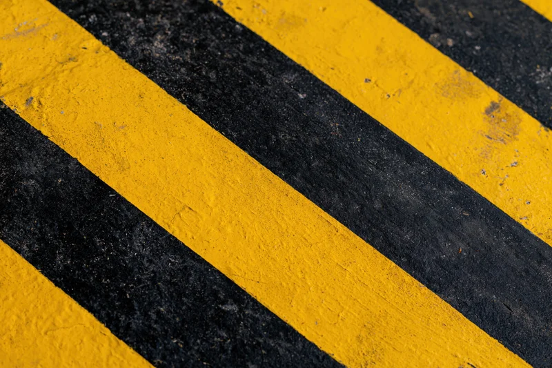 Diagonal yellow and black stripes painted on an industrial pavement surface