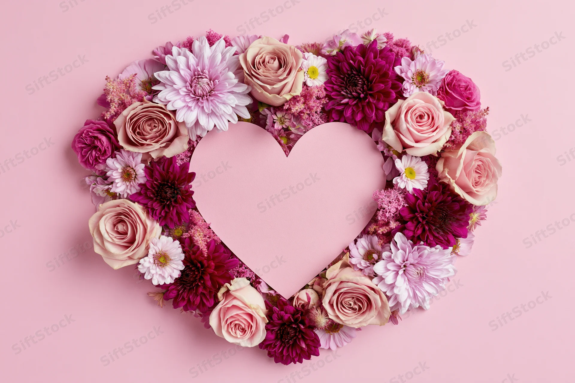 Heart-shaped floral arrangement made of pink and magenta roses and dahlia on a pink background