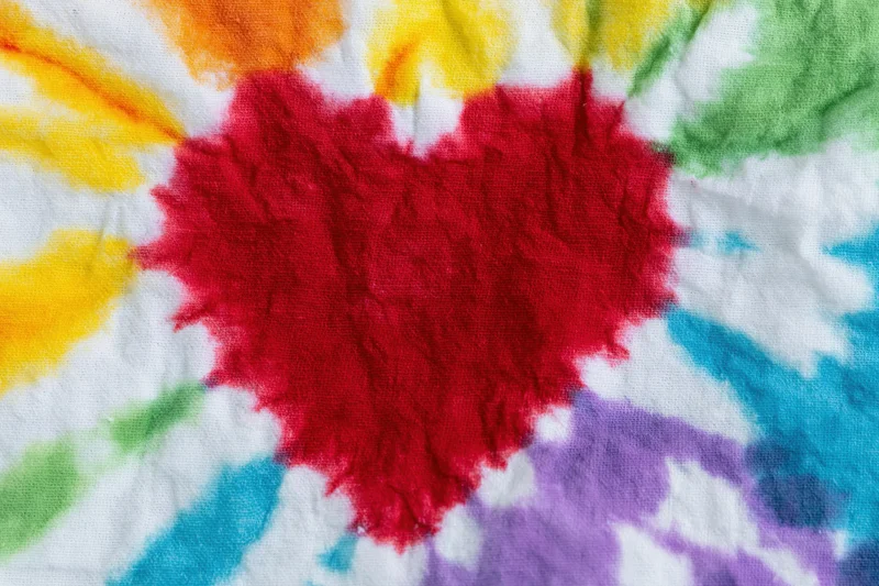 Close-up of tie-dye cotton fabric with red heart and rainbow colors filling the frame