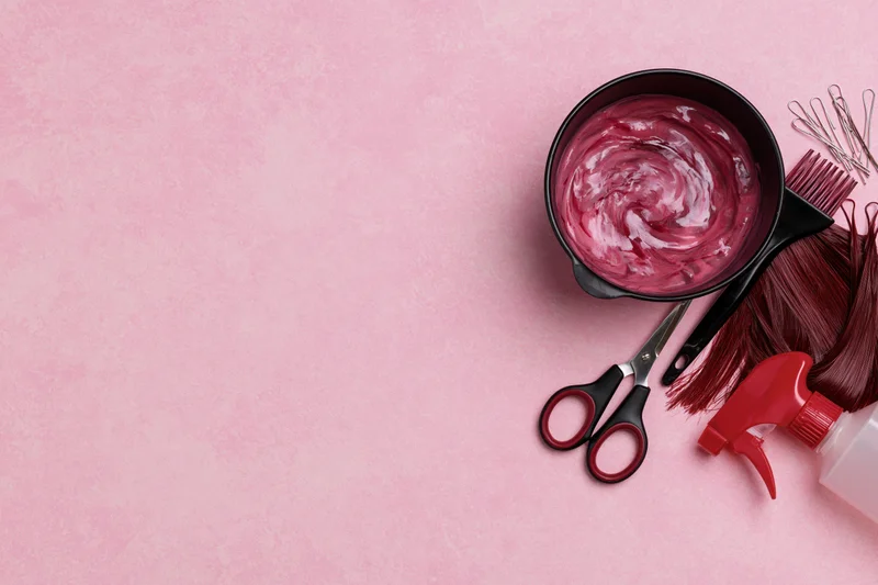 Hair dyeing tools arranged on pink surface with copyspace