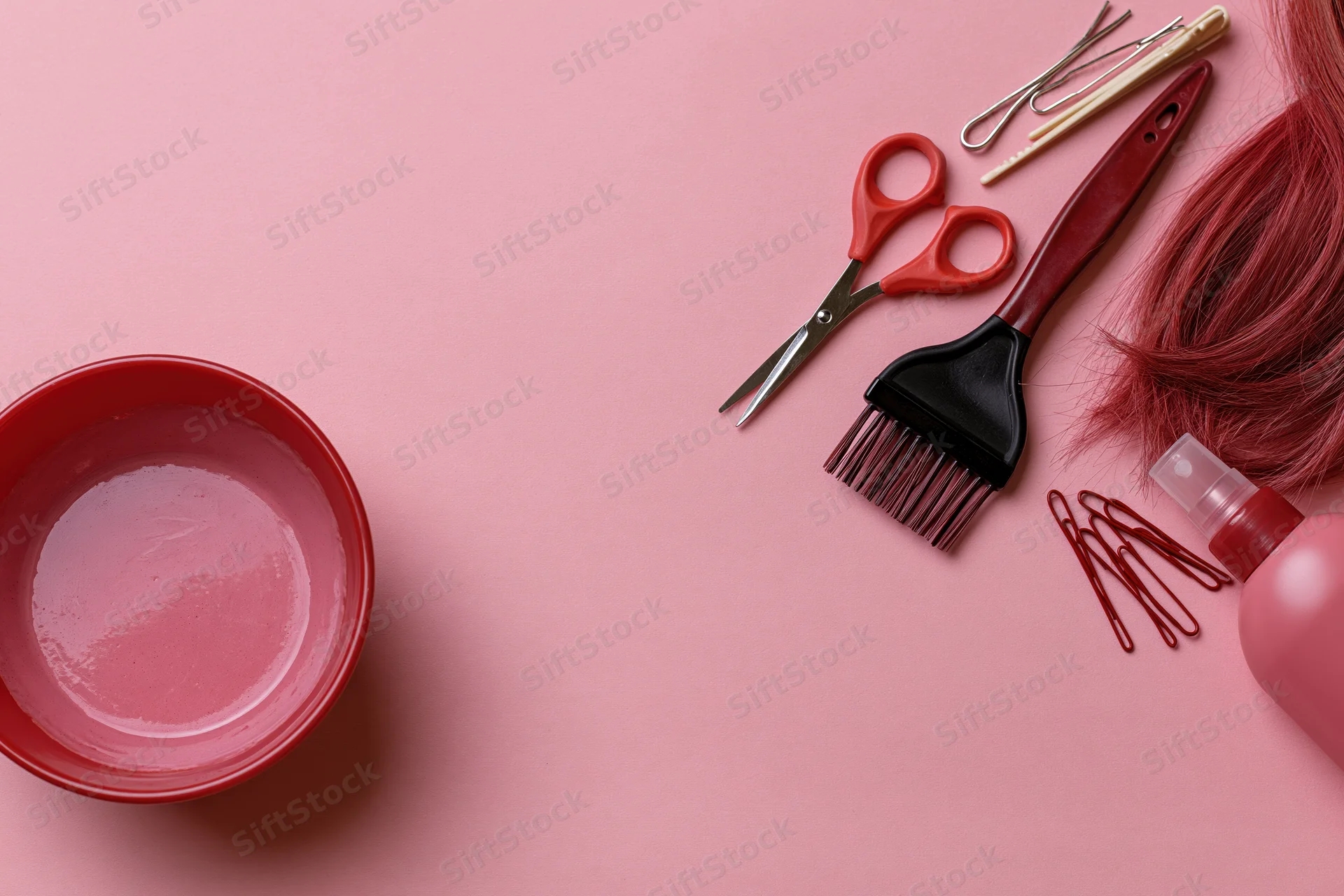 Hair dyeing tools arranged in flat lay on pink surface