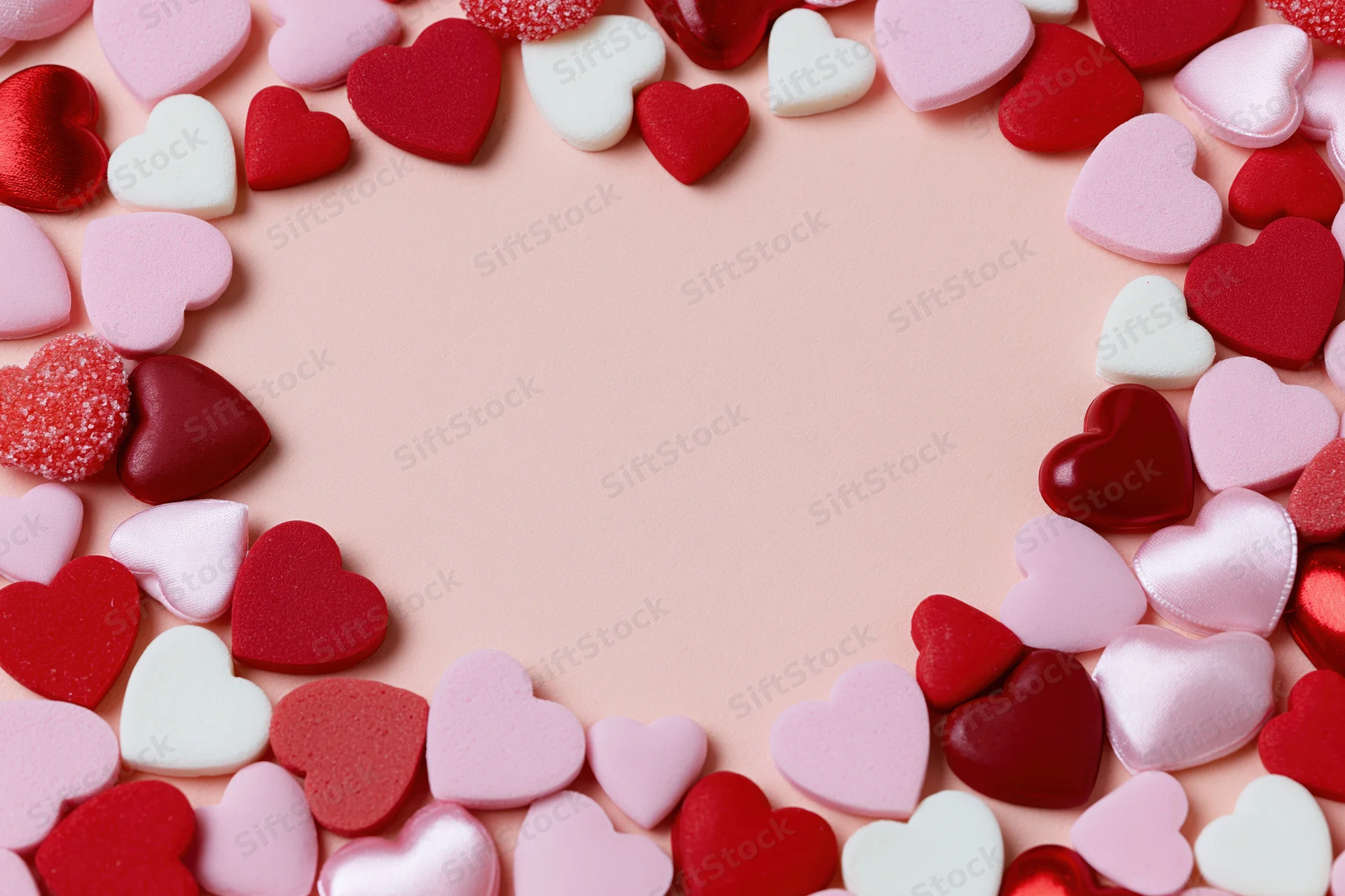Heart shapes arranged in a circular frame on a pink surface with copyspace in the center