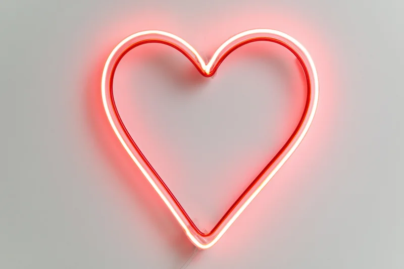 Glowing red neon heart outline mounted on a white wall