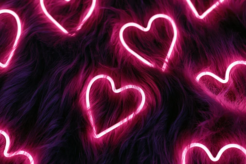 Glowing pink neon heart outlines scattered across dark faux fur surface