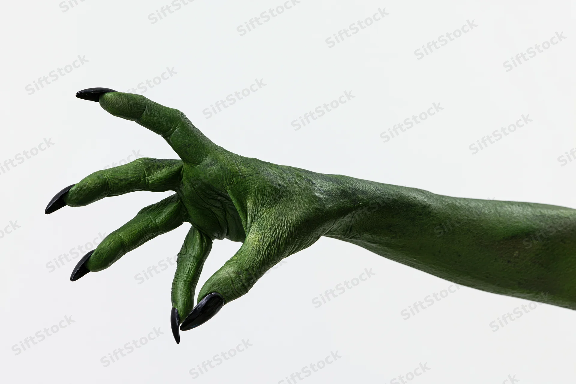 Green-painted hand with black claws reaching forward against white background