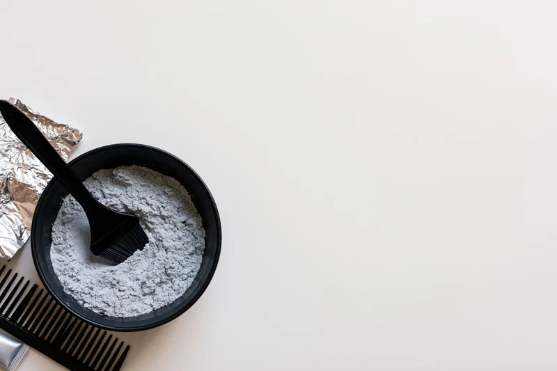 Hair coloring tools arranged in the bottom-left corner on a white surface