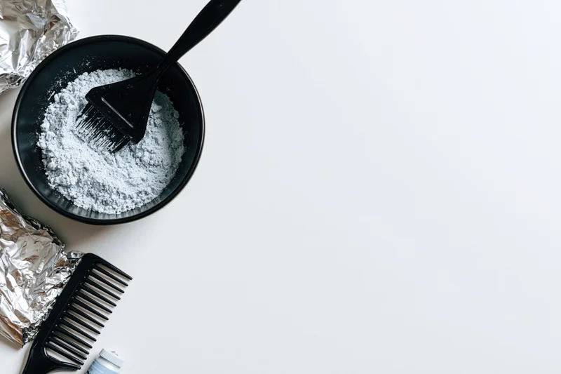 Hair coloring tools arranged in bottom-left corner on white surface