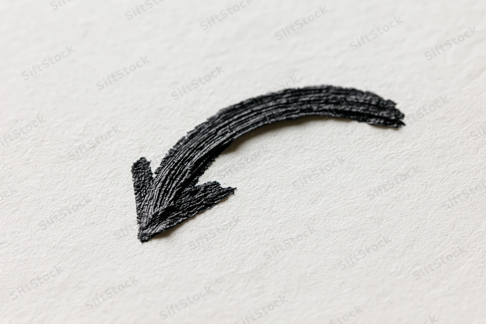 Hand-drawn black ink arrow curving downward left on white paper