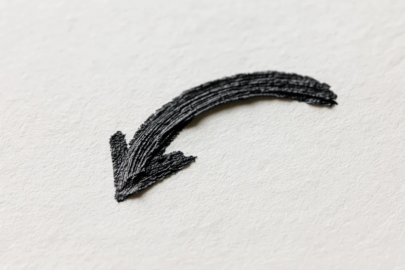 Hand-drawn black ink arrow curving downward left on white paper