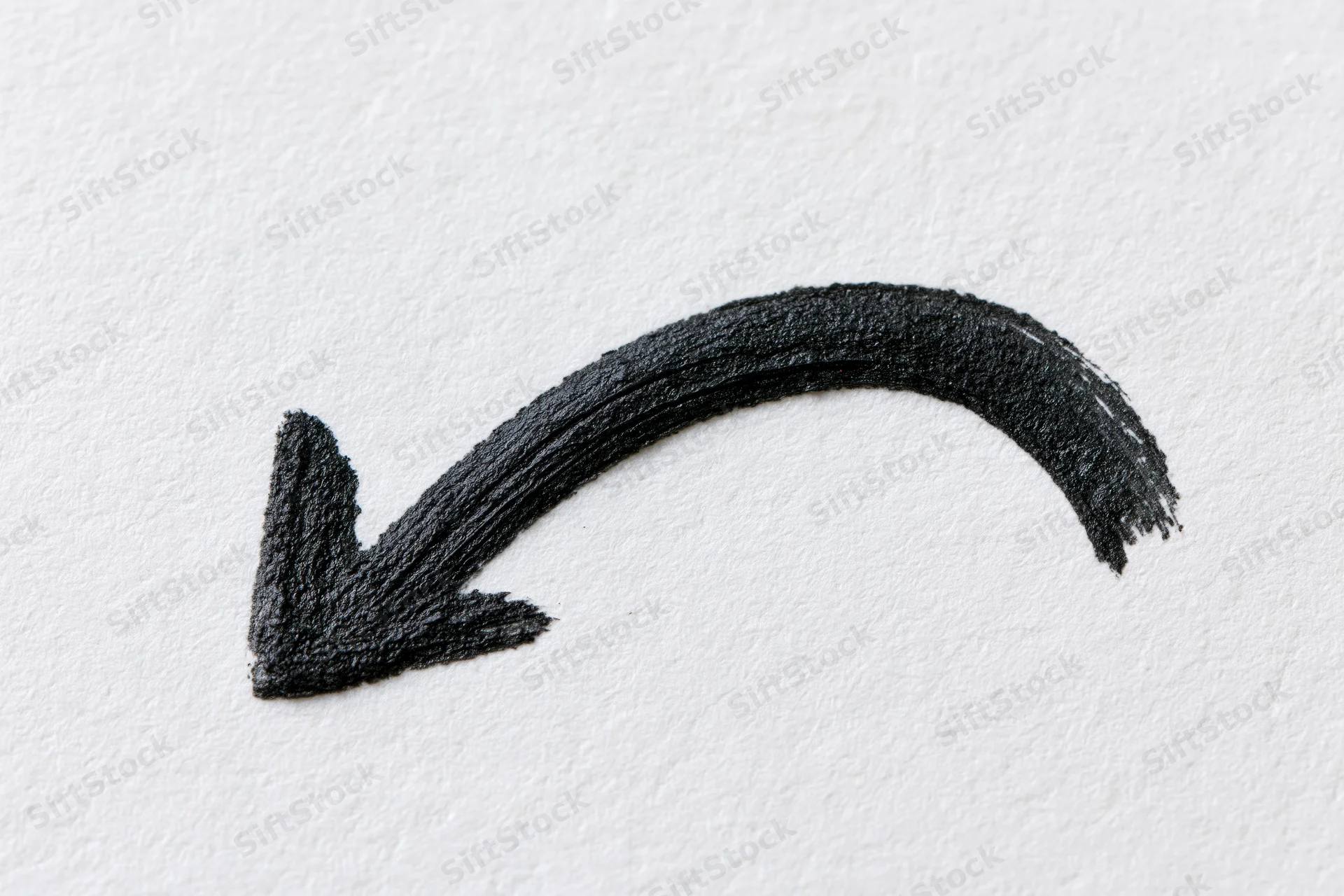 Hand-drawn black ink arrow curving downward left on white paper