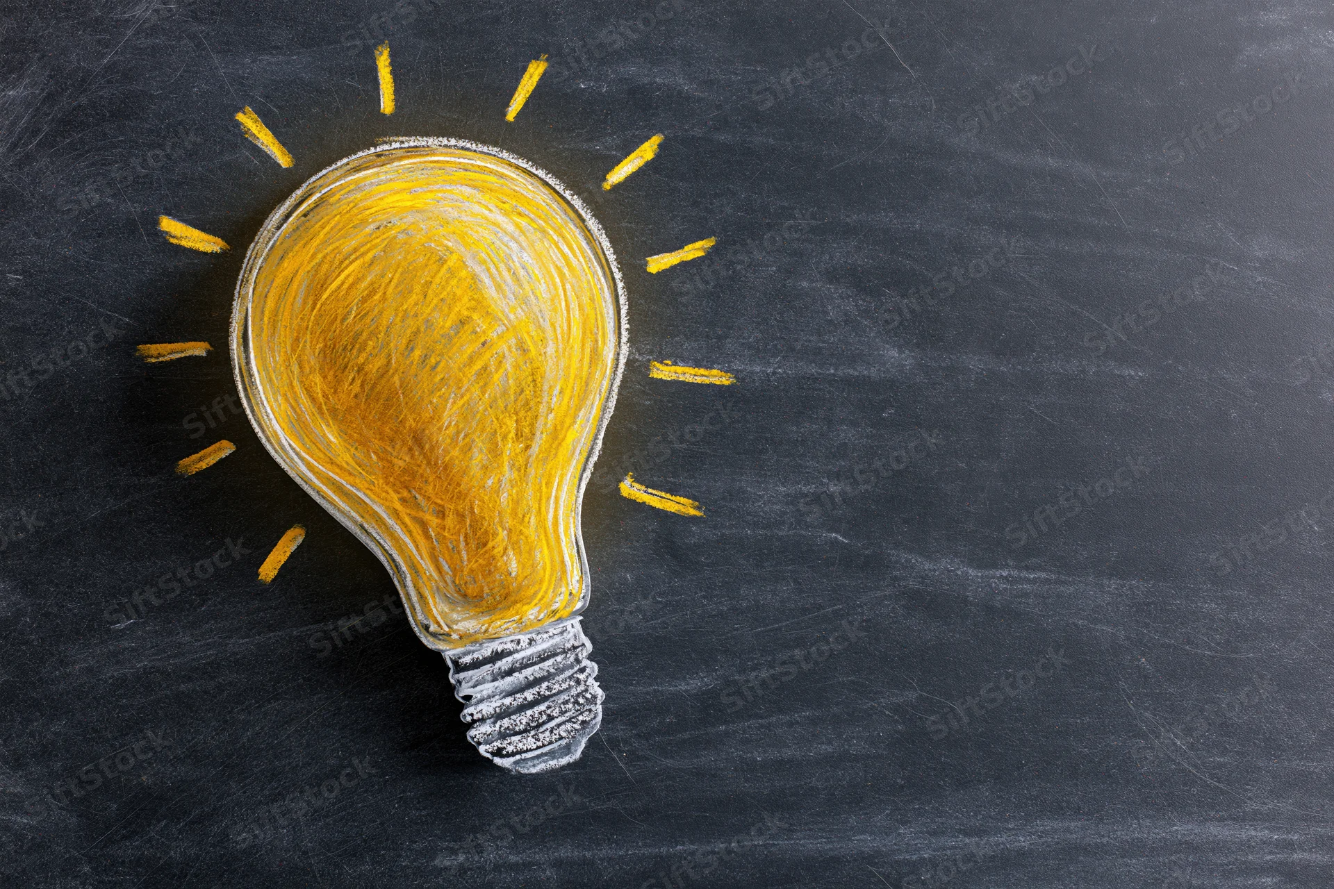 Hand-drawn chalk light bulb sketch on dark blackboard surface