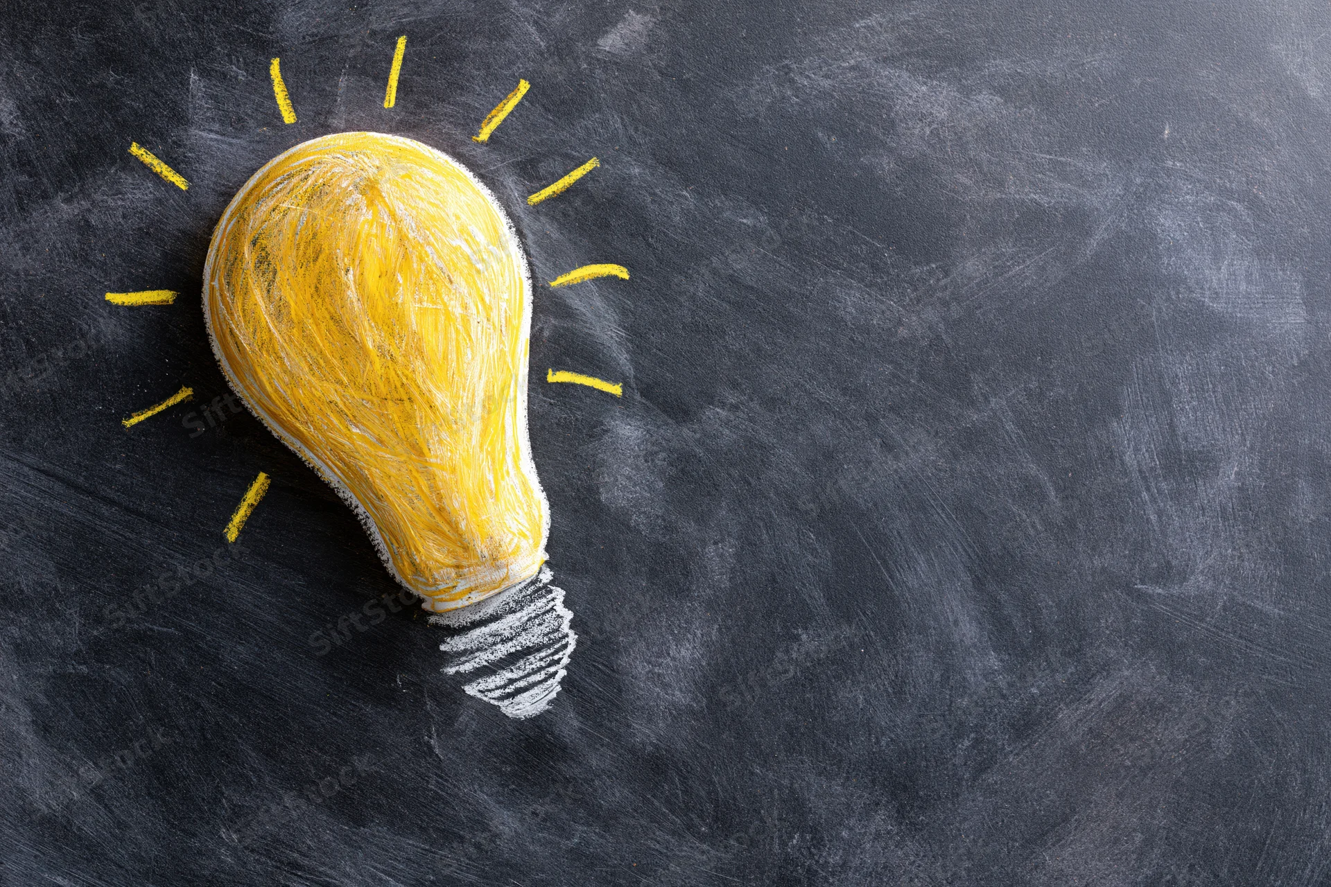 Chalk-drawn lightbulb on blackboard surface with radiating lines indicating illumination