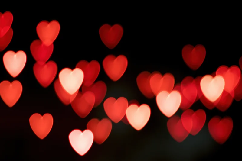 Heart-shaped bokeh lights glowing softly against a dark background