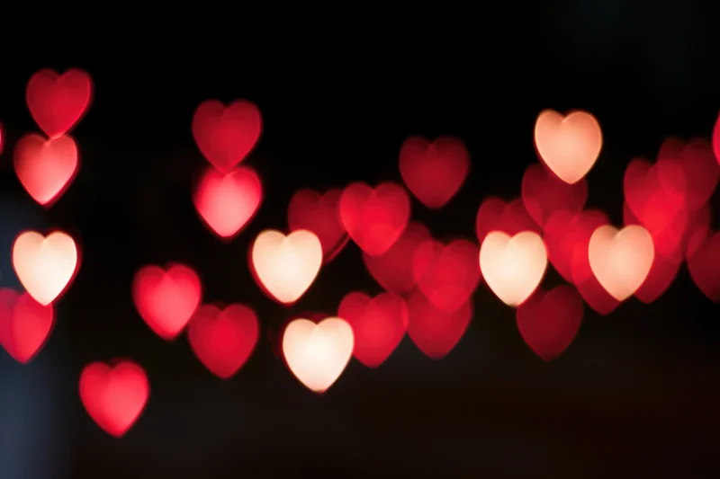 Heart-shaped bokeh lights scattered across a dark background