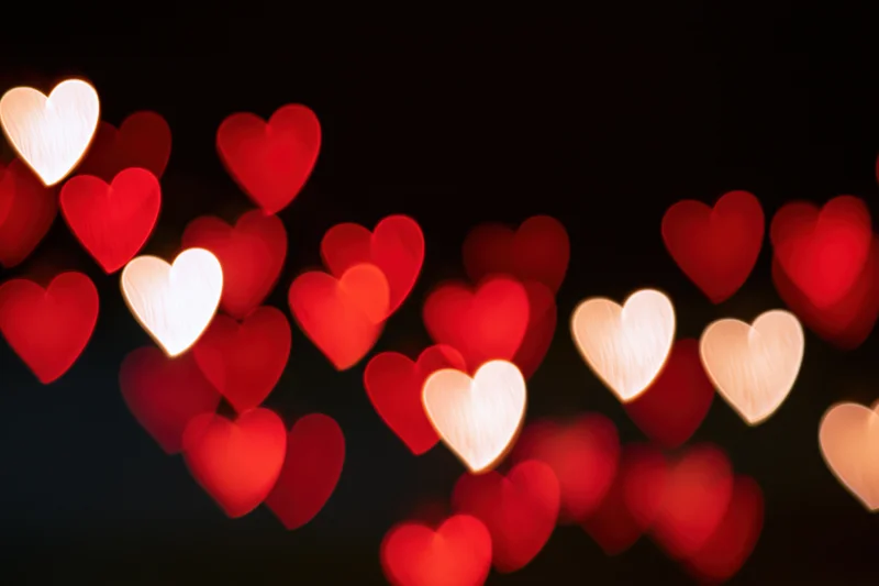 Heart-shaped bokeh lights glowing softly against a dark background