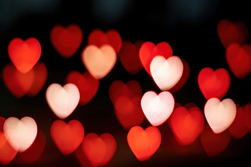 Heart-shaped bokeh lights glowing softly against a dark background
