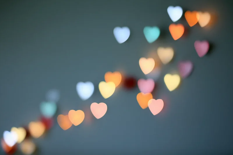 Heart-shaped bokeh lights scattered across a dark background in soft focus