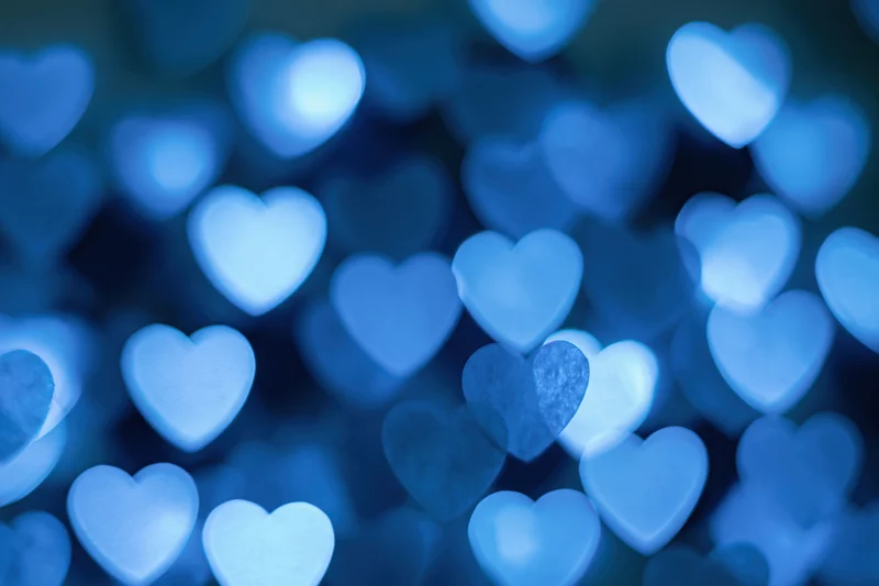 Heart-shaped bokeh lights scattered across a dark blue background