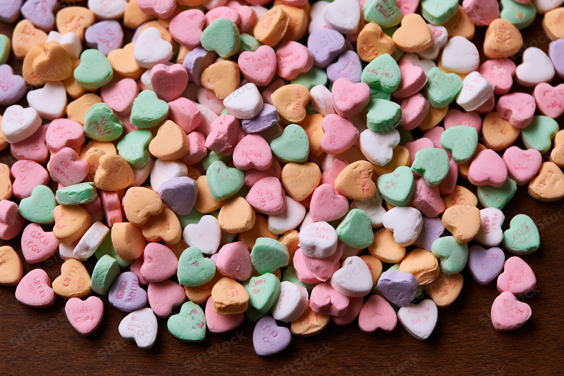 Scattered pastel conversation hearts on wooden surface