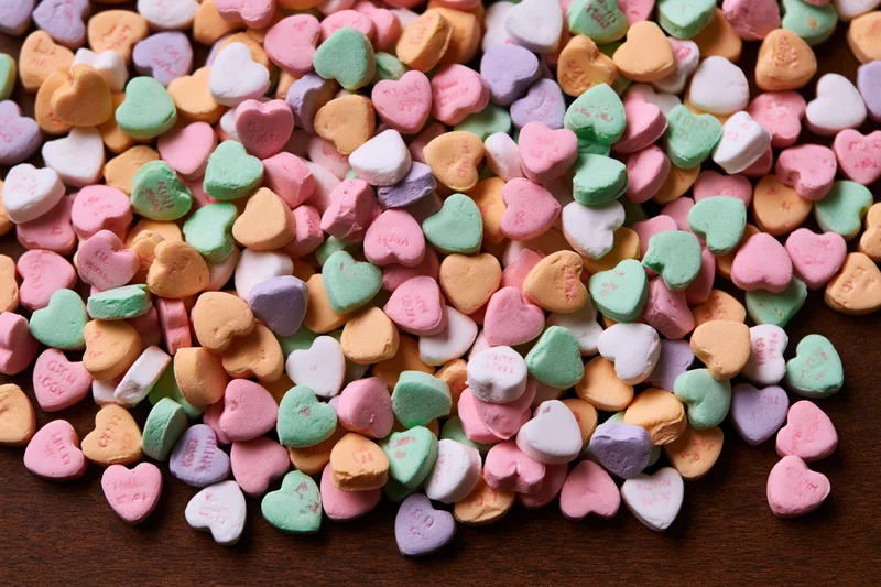 Scattered pastel conversation hearts on wooden surface