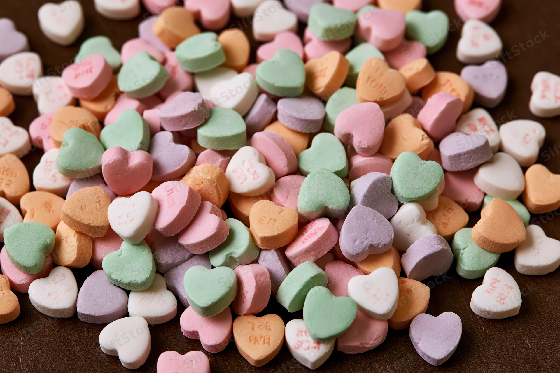 Scattered pastel conversation hearts on wooden surface
