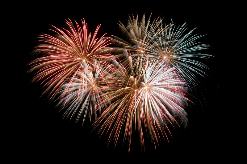 Fireworks bursting in a heart-shaped pattern against a dark night sky