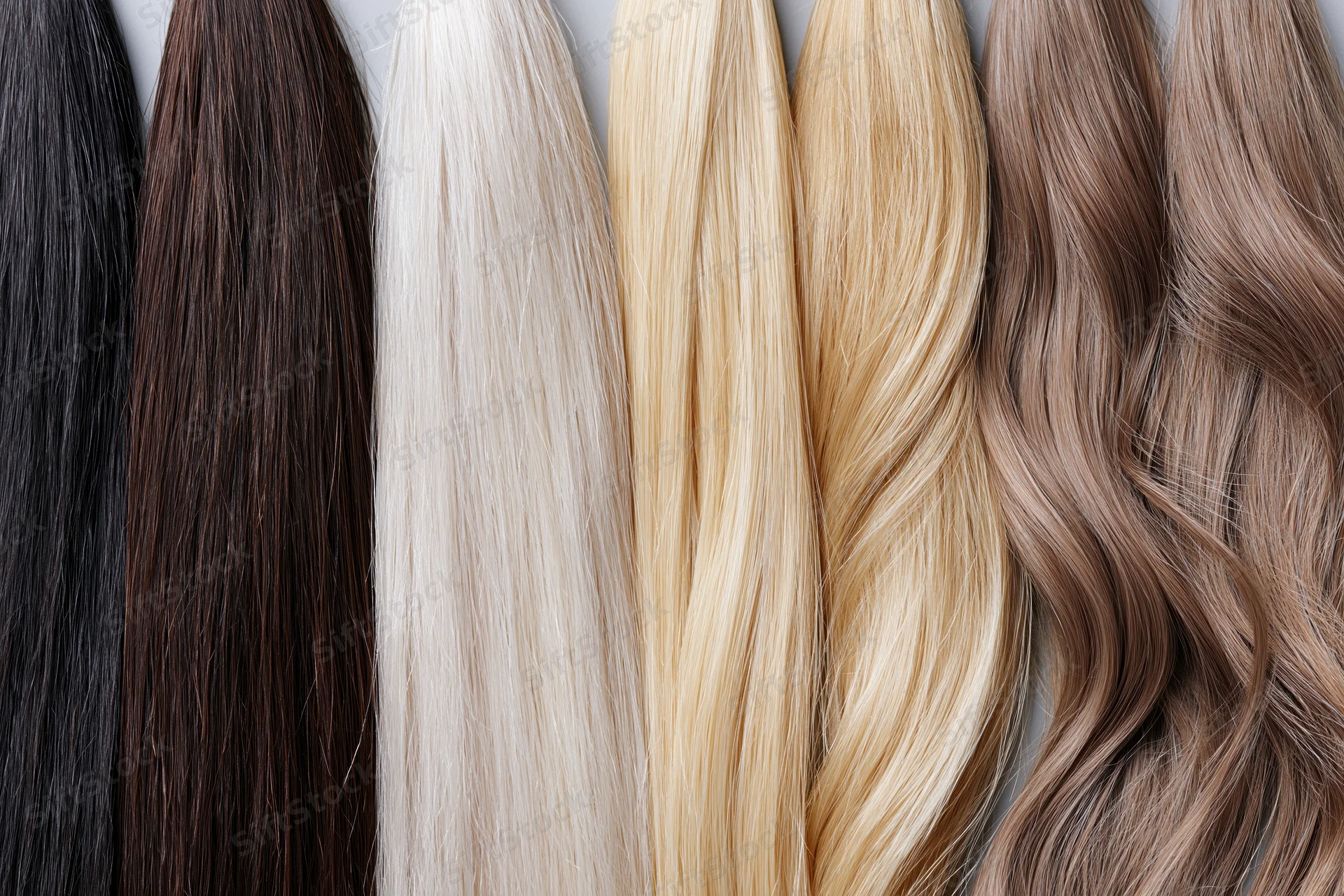 Multiple hair extension wefts arranged side by side in a row showcasing different colors and textures