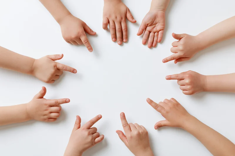 Multiple child hands pointing inward in a circle on white background