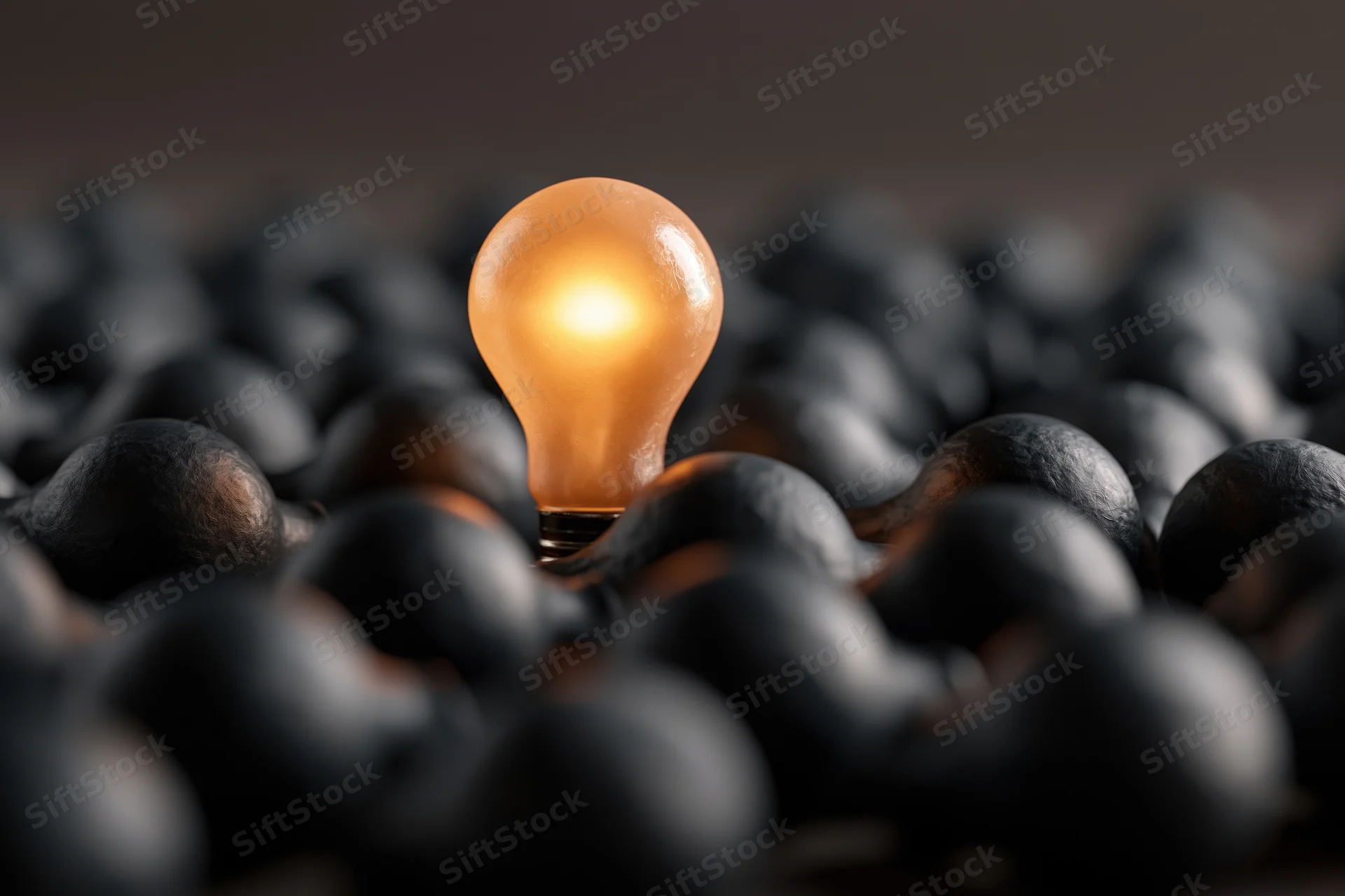Glowing incandescent light bulb standing among unlit bulbs in a dark setting