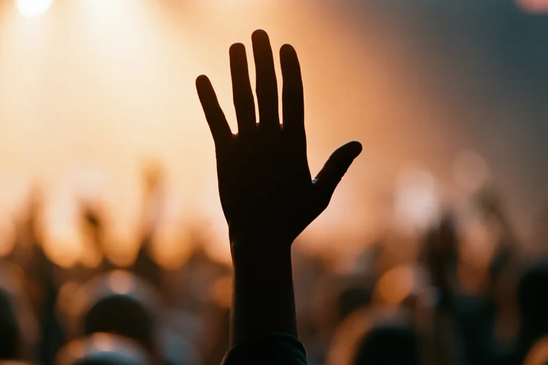 Hand raised high in silhouette above a crowd at a concert