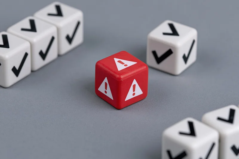 Red warning dice among white checkmark dice on gray surface