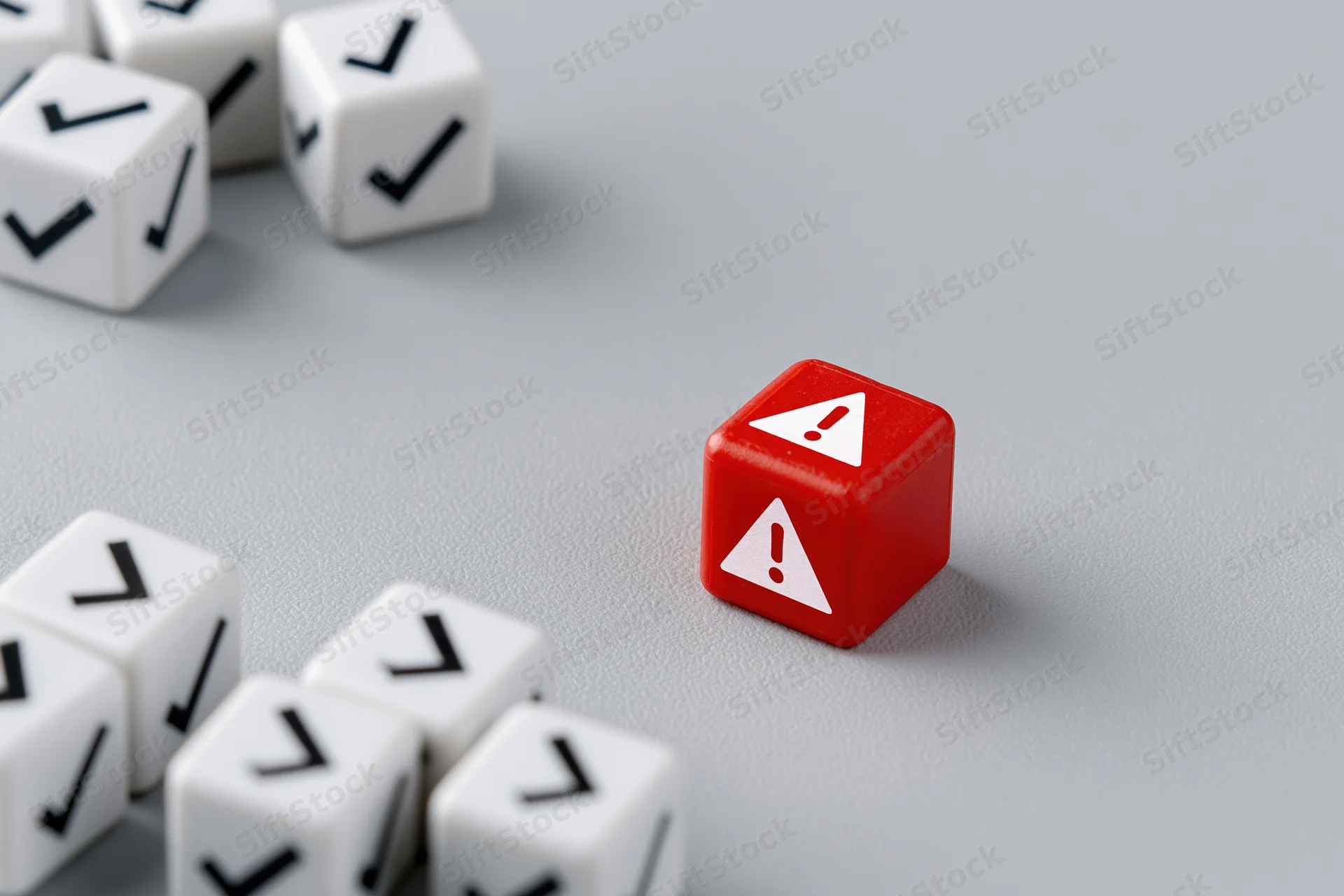 Red cube with warning symbol among white cubes with checkmarks on gray surface