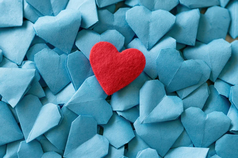 Red felt heart resting on pile of blue origami hearts