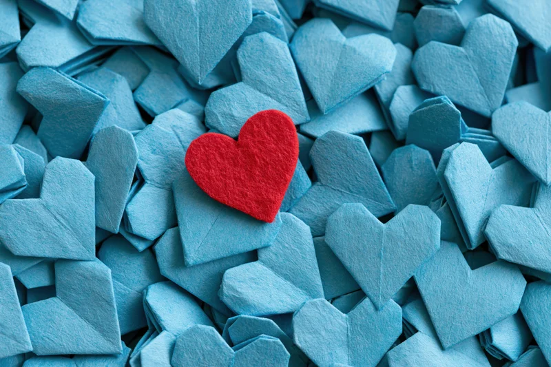 Red felt heart resting on pile of blue origami hearts