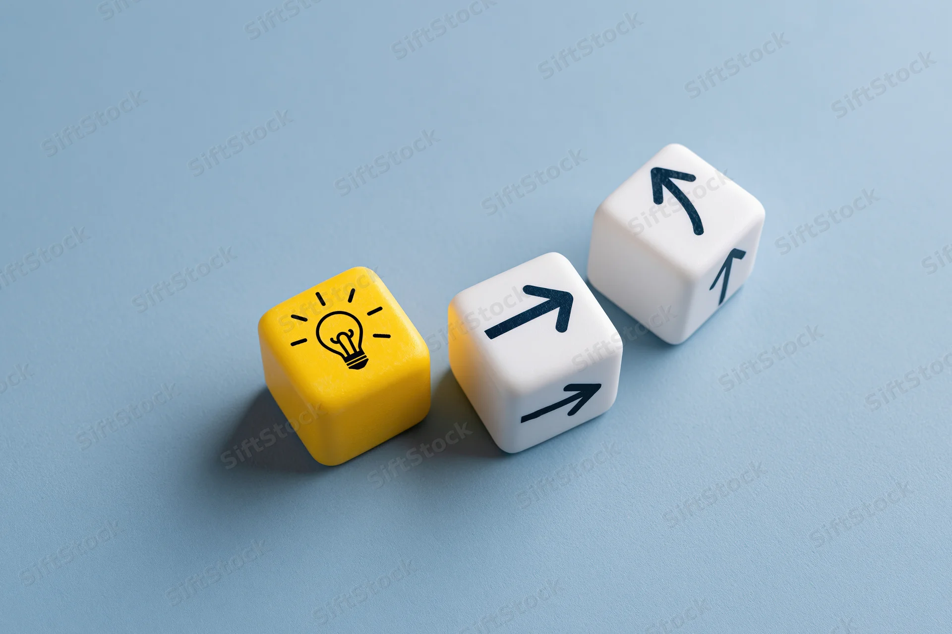Three cubes with lightbulb and arrow symbols arranged on a blue surface