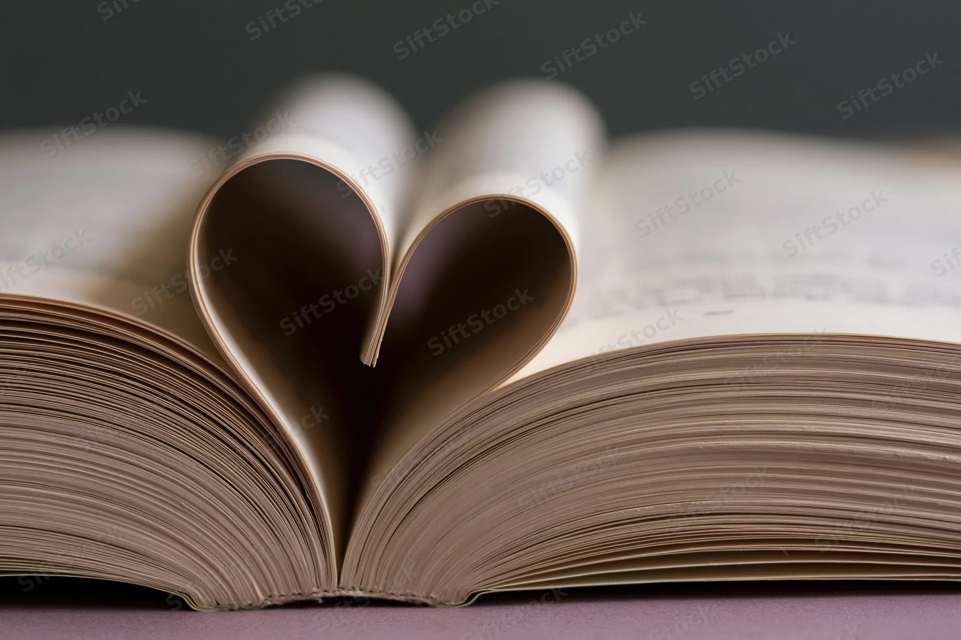 Open book with pages folded into a heart shape on a flat surface
