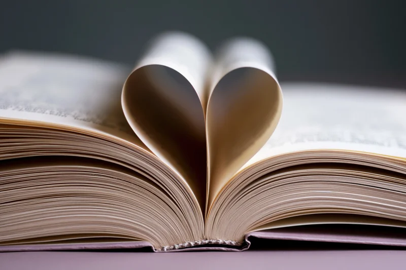 Open book with pages folded into a heart shape on a flat surface
