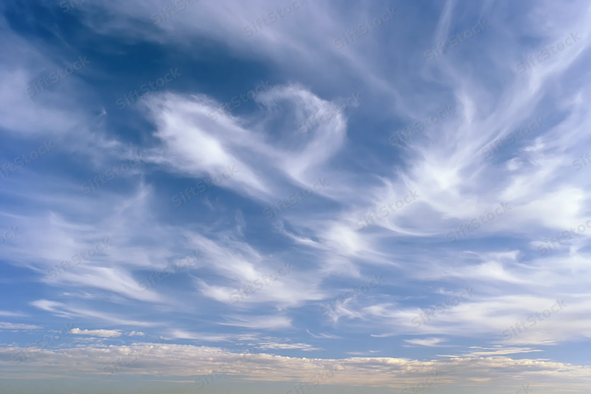 Open sky with scattered wispy cirrus clouds during daytime