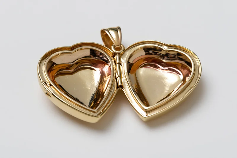 Open gold heart-shaped locket pendant lying flat with both halves visible on white surface