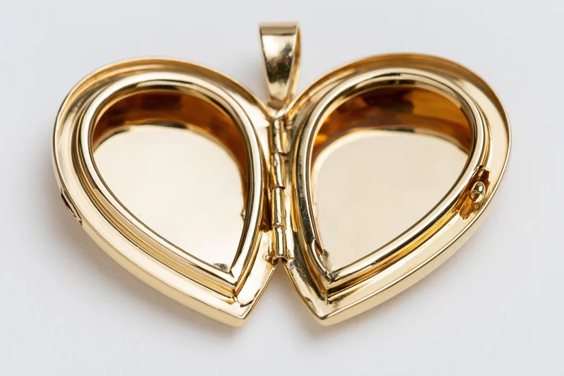 Open gold heart-shaped locket pendant lying flat on white surface