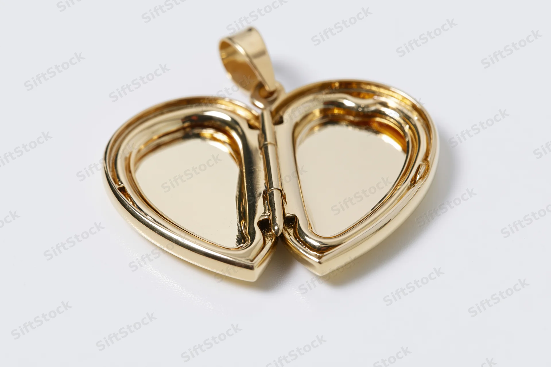 Open gold heart-shaped locket pendant lying flat on white surface