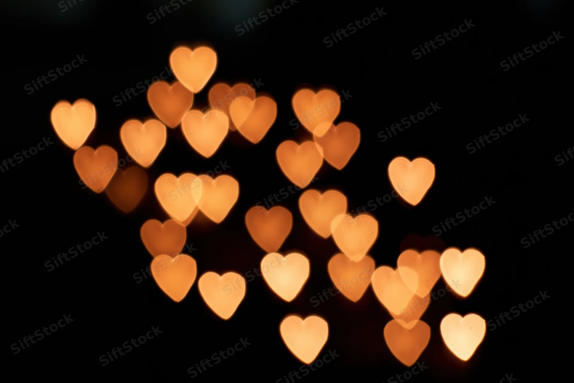 Heart-shaped bokeh lights glowing softly against a dark background with copyspace