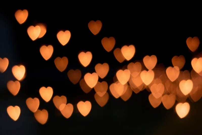 Heart-shaped bokeh lights glowing softly against a dark background
