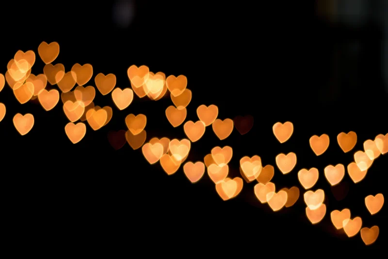 Heart-shaped bokeh lights glowing softly against a dark background with copyspace
