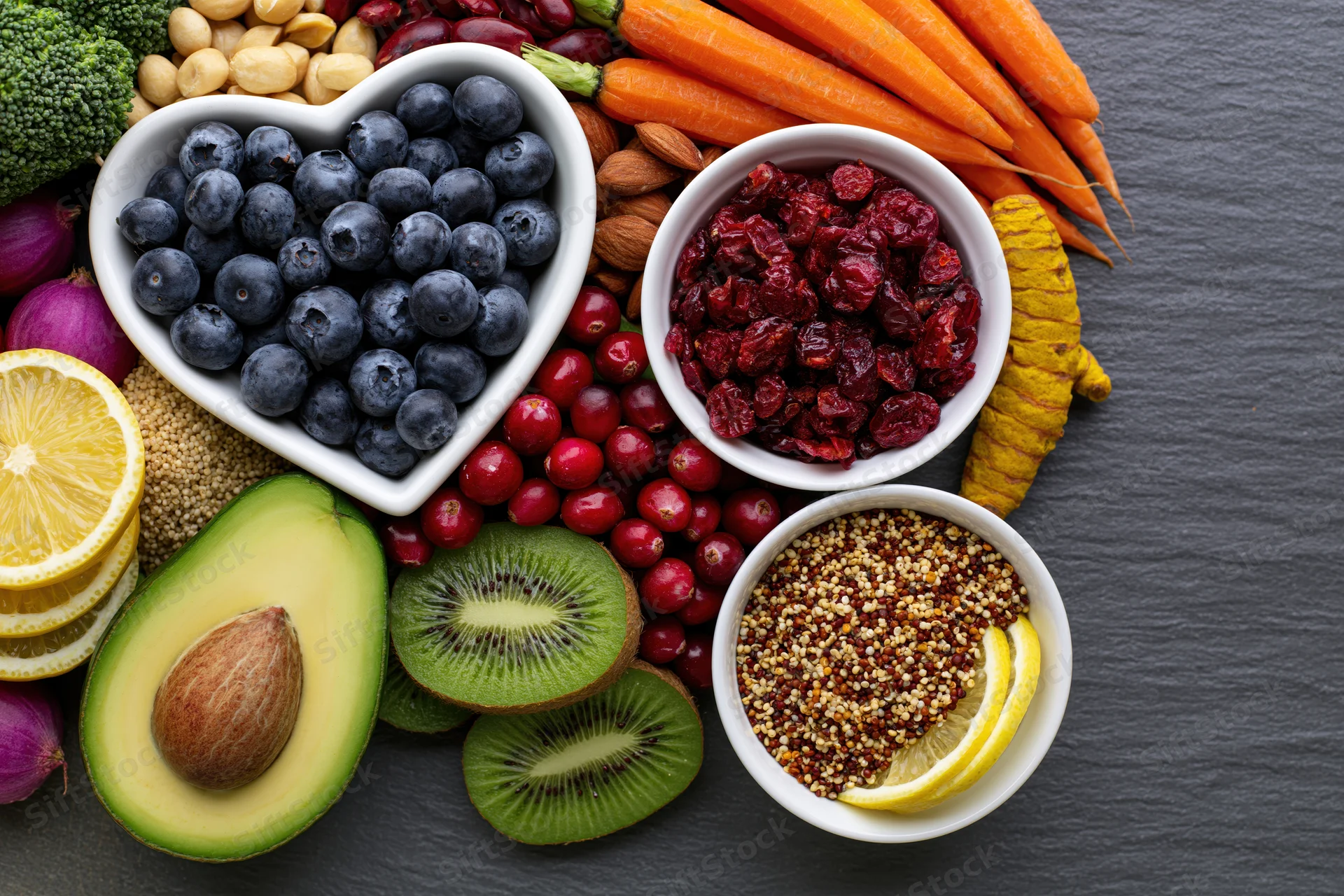 Overhead flat lay of fresh fruits vegetables nuts and grains arranged on slate surface