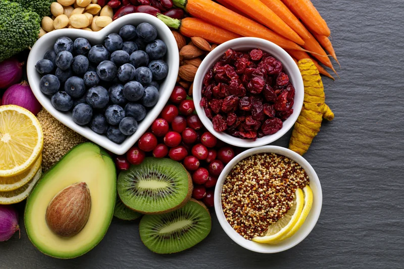 Overhead flat lay of fresh fruits vegetables nuts and grains arranged on slate surface