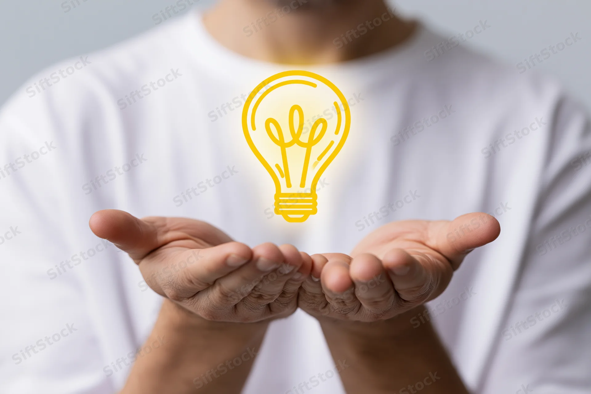 Man holding glowing lightbulb symbol in cupped hands