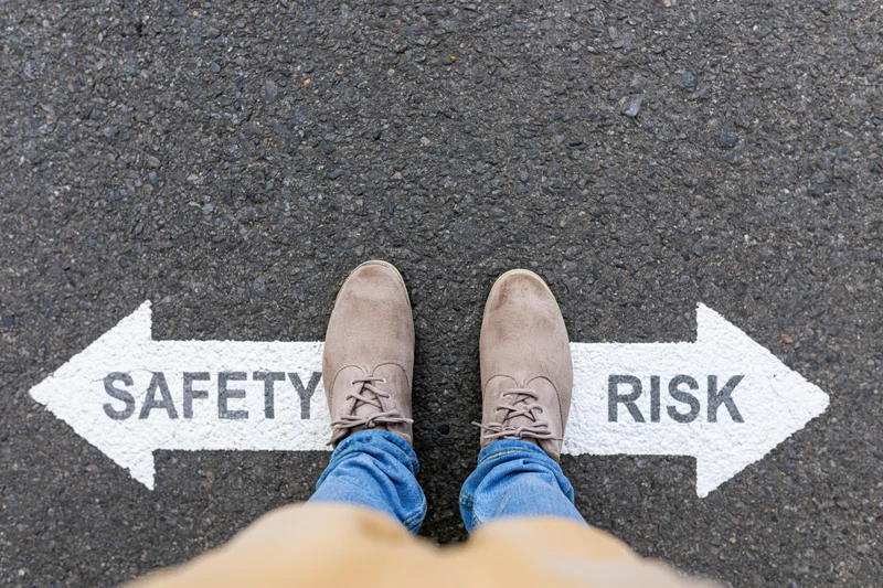 Person standing at crossroads with safety and risk arrows painted on asphalt pavement